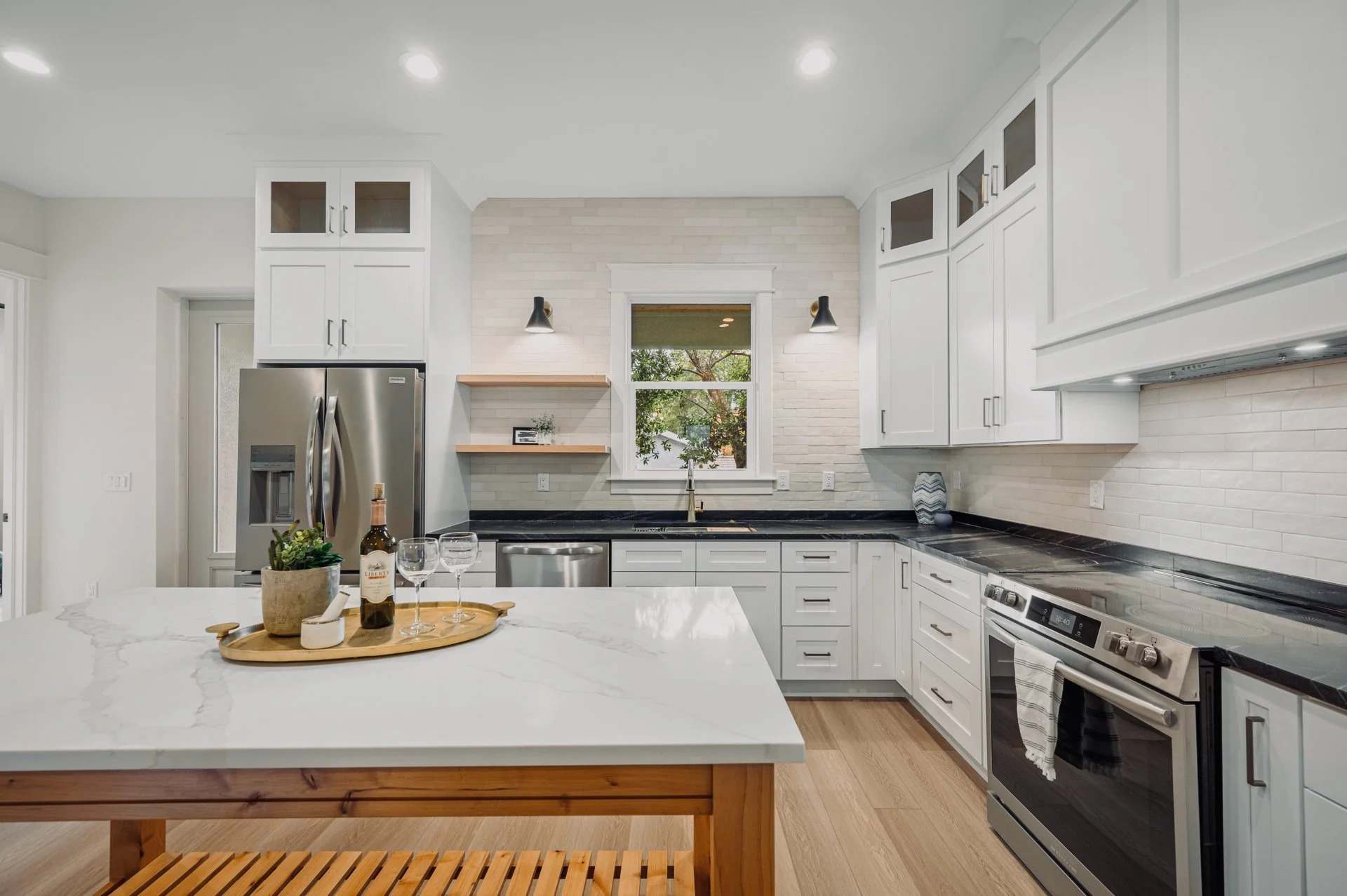 White shaker kitchen with soapstone counters, open shelving, and subway tile backsplash