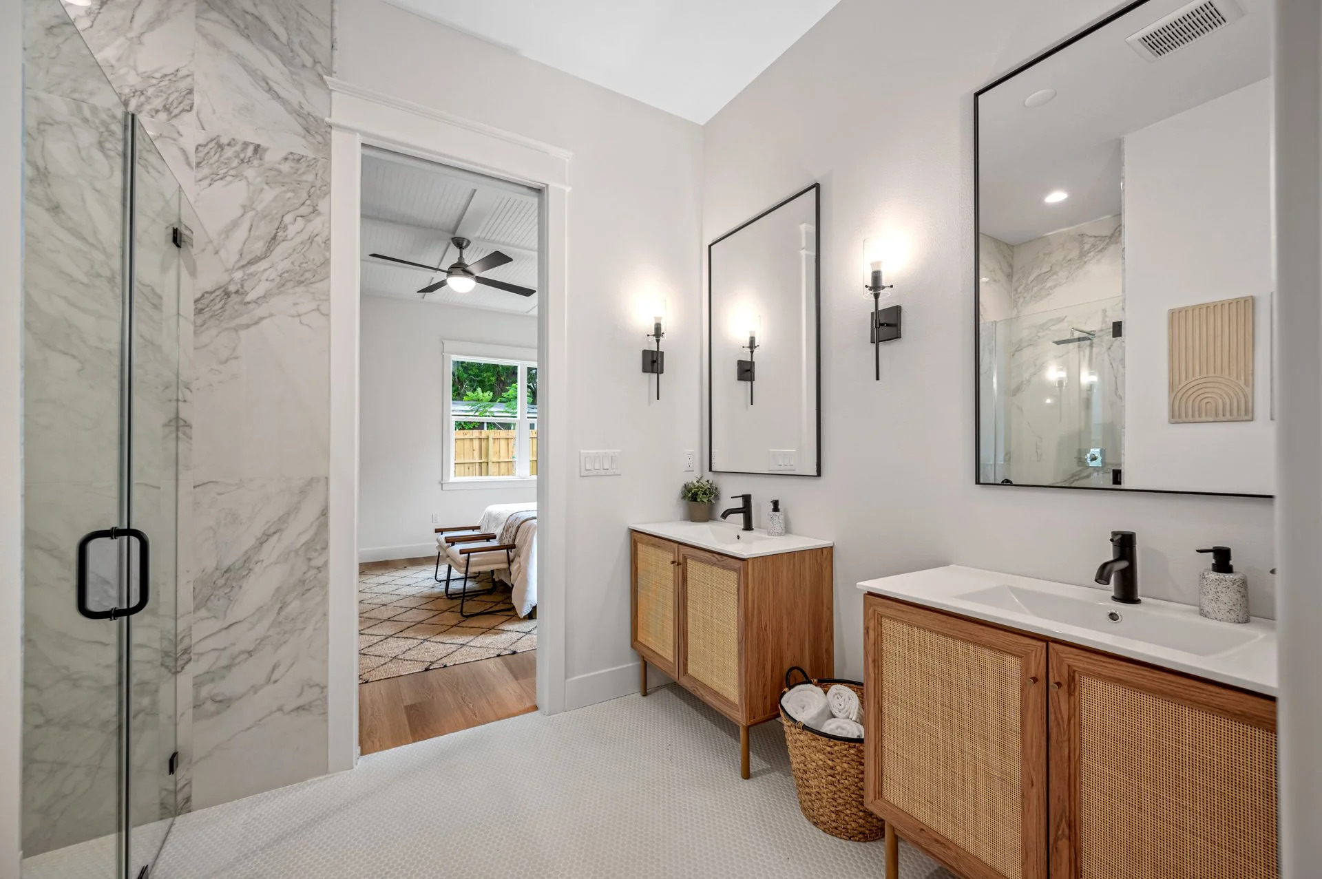 Master bathroom with marble shower, rattan vanities, and matte black fixtures