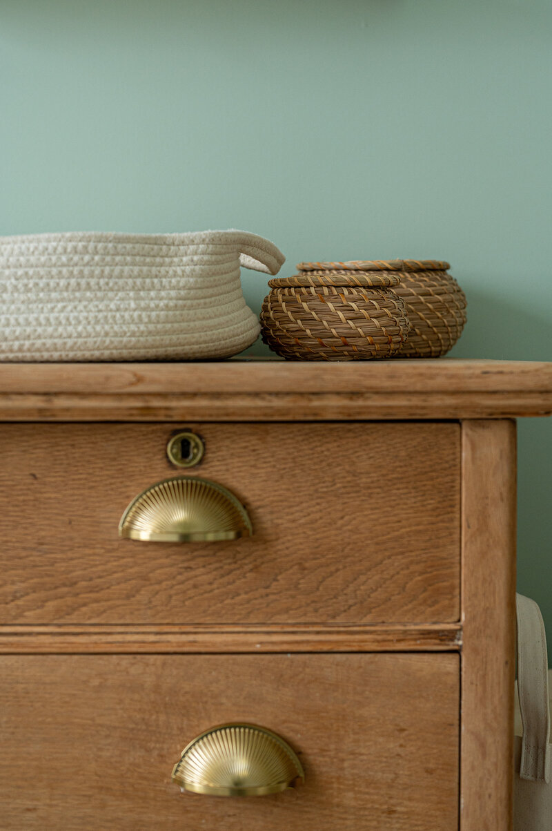 Nursery detail — vintage oak dresser with natural woven baskets