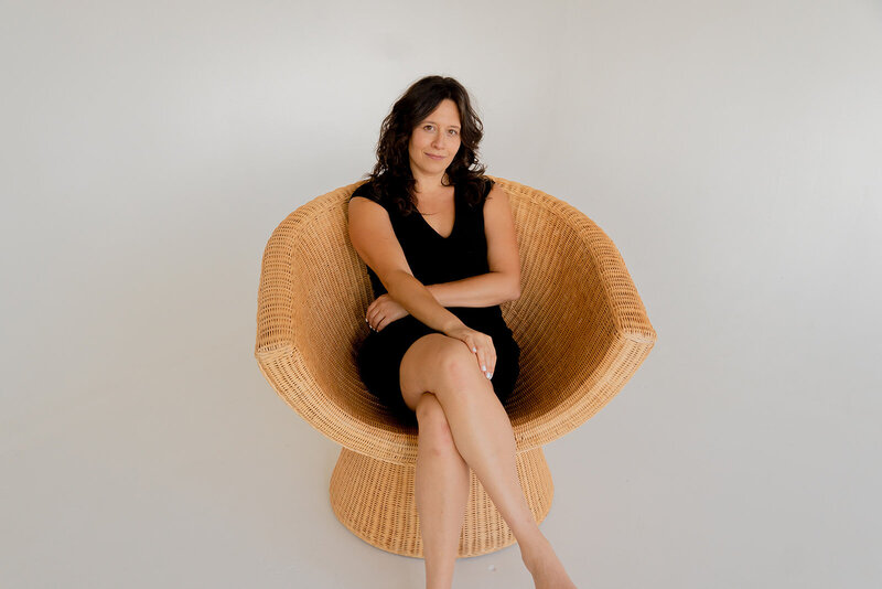 Ashley Spanovich seated in woven rattan chair, black dress