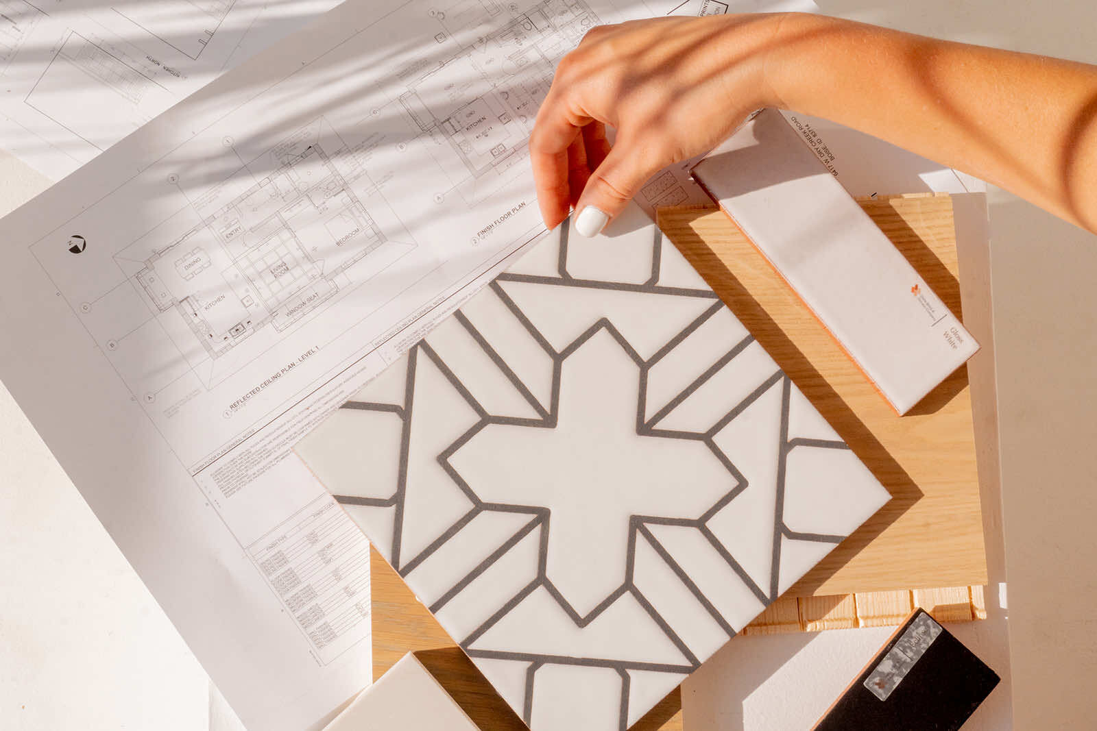 Hand selecting tile samples over architectural blueprints