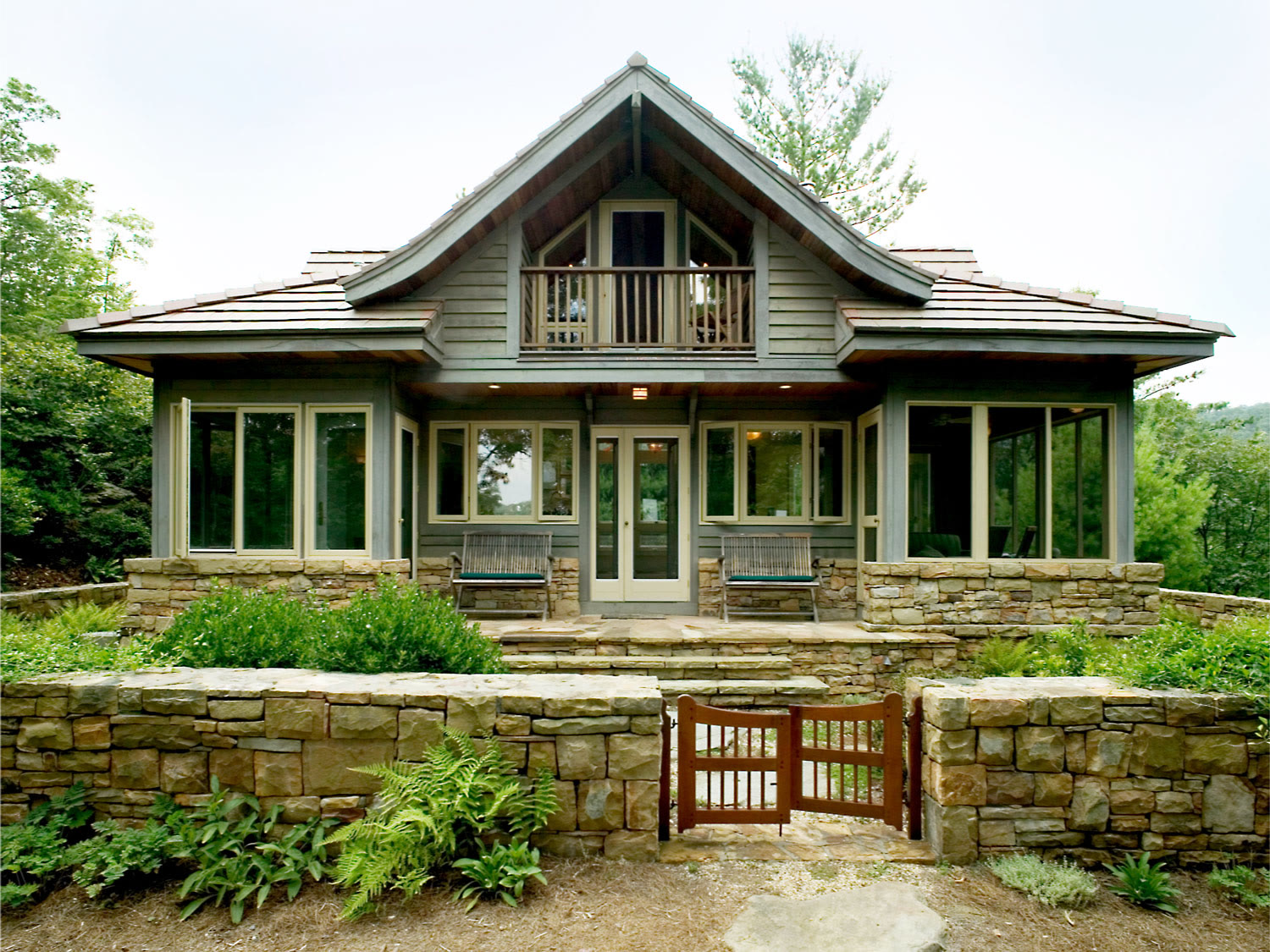 Vastu-inspired timber and stone home with deck and gable roof 