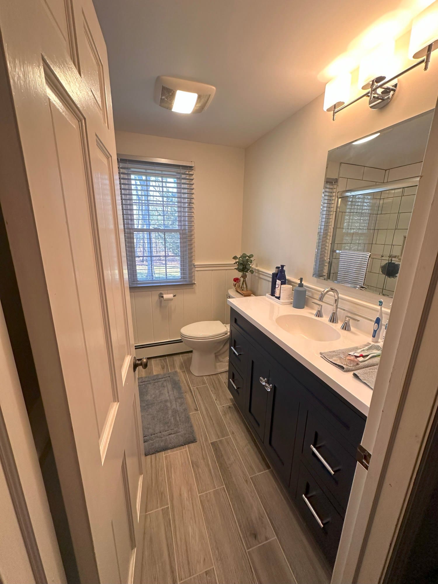 Completed CT bathroom remodel — navy vanity, white counter, wood-look tile floor