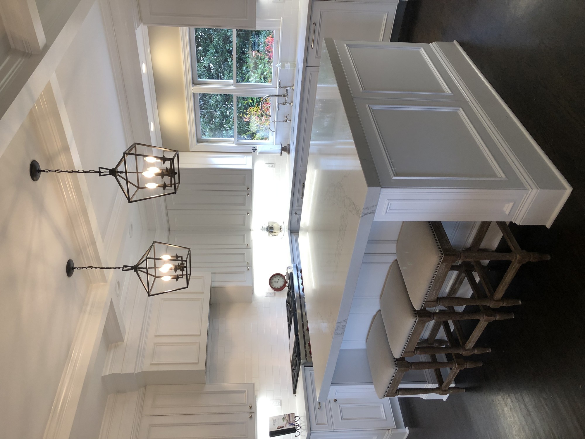 White luxury kitchen with marble countertops and cage pendant lights