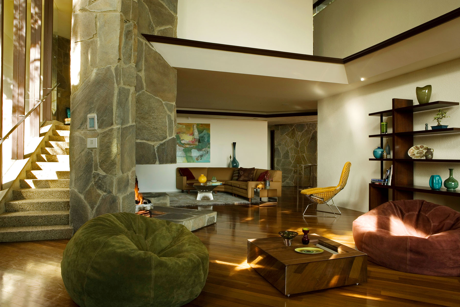 Lautner Wolff House — double-height living room with stone chimney and warm light