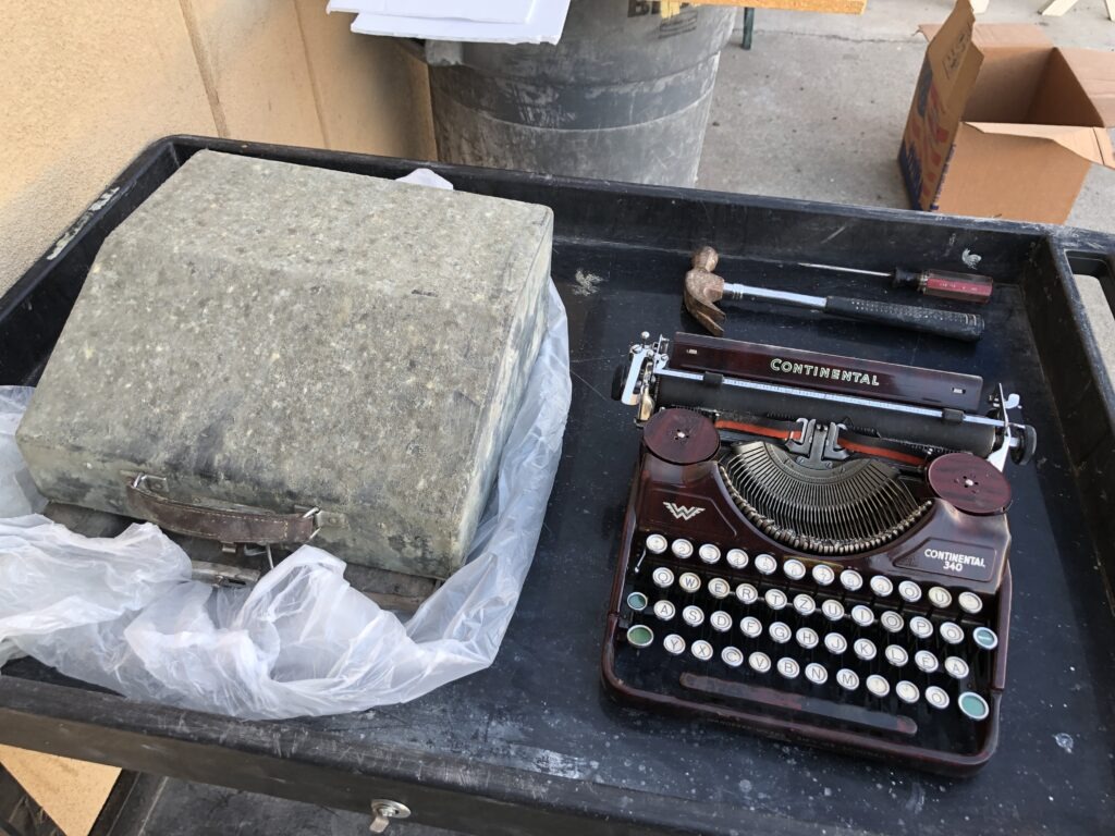 A typewriter beside its case on a work surface