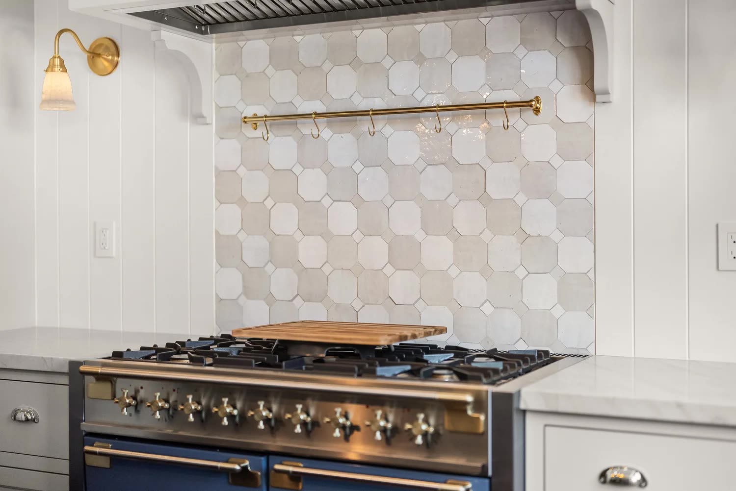Hexagonal cement tile backsplash with brass pot rail and navy range