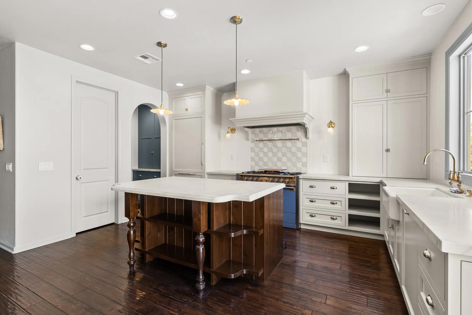 Luxury kitchen renovation with marble waterfall island and brass pendants