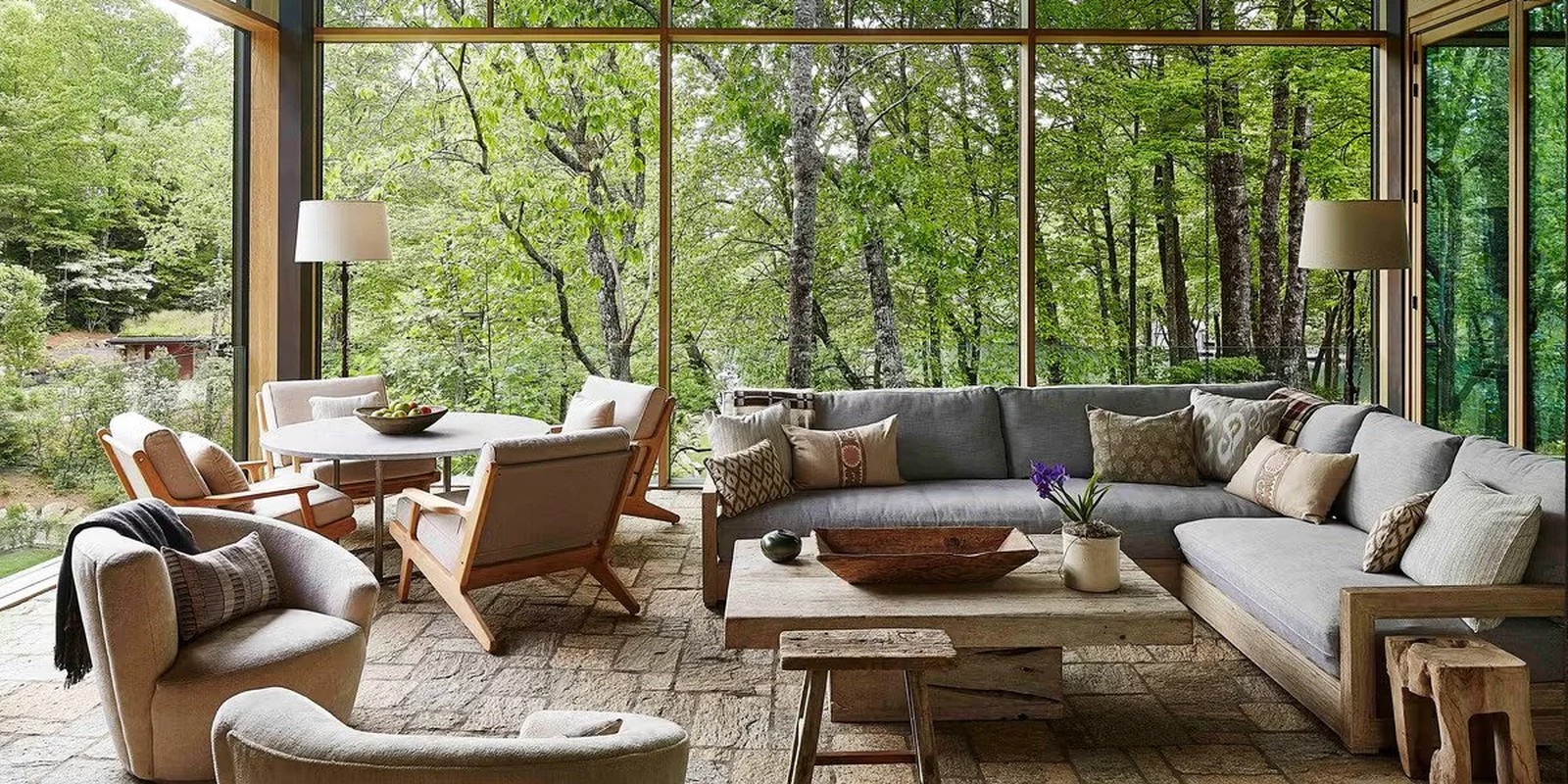 Biophilic sunroom with floor-to-ceiling glass and forest view (Rachel's site hero — stock photograph, Unsplash)