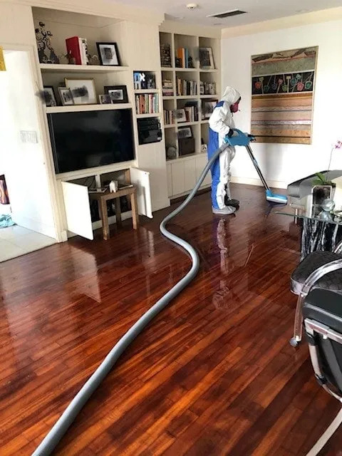 Technician extracting water from hardwood floors with commercial equipment