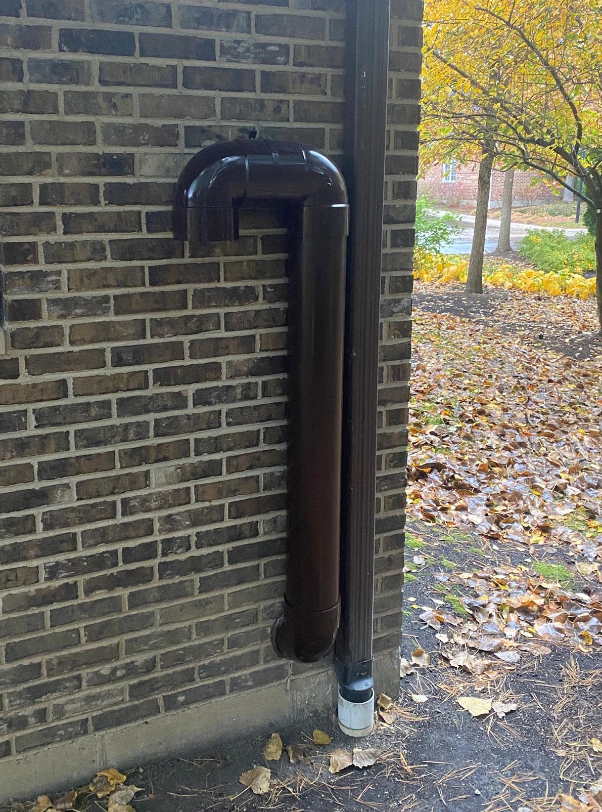 Exterior wall ventilation termination in dark bronze on brick façade