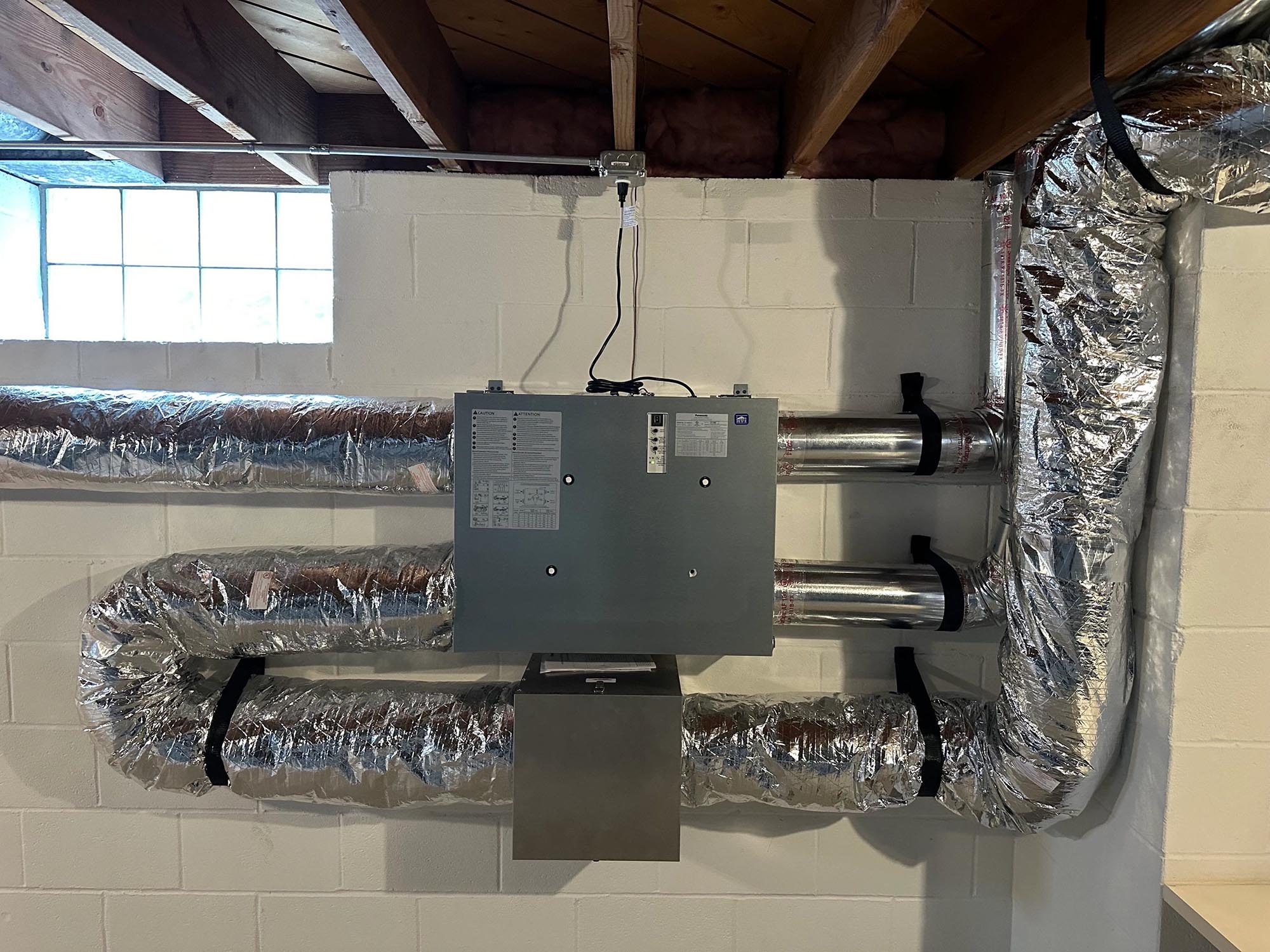 Basement ventilation unit with cinder block wall and window daylight