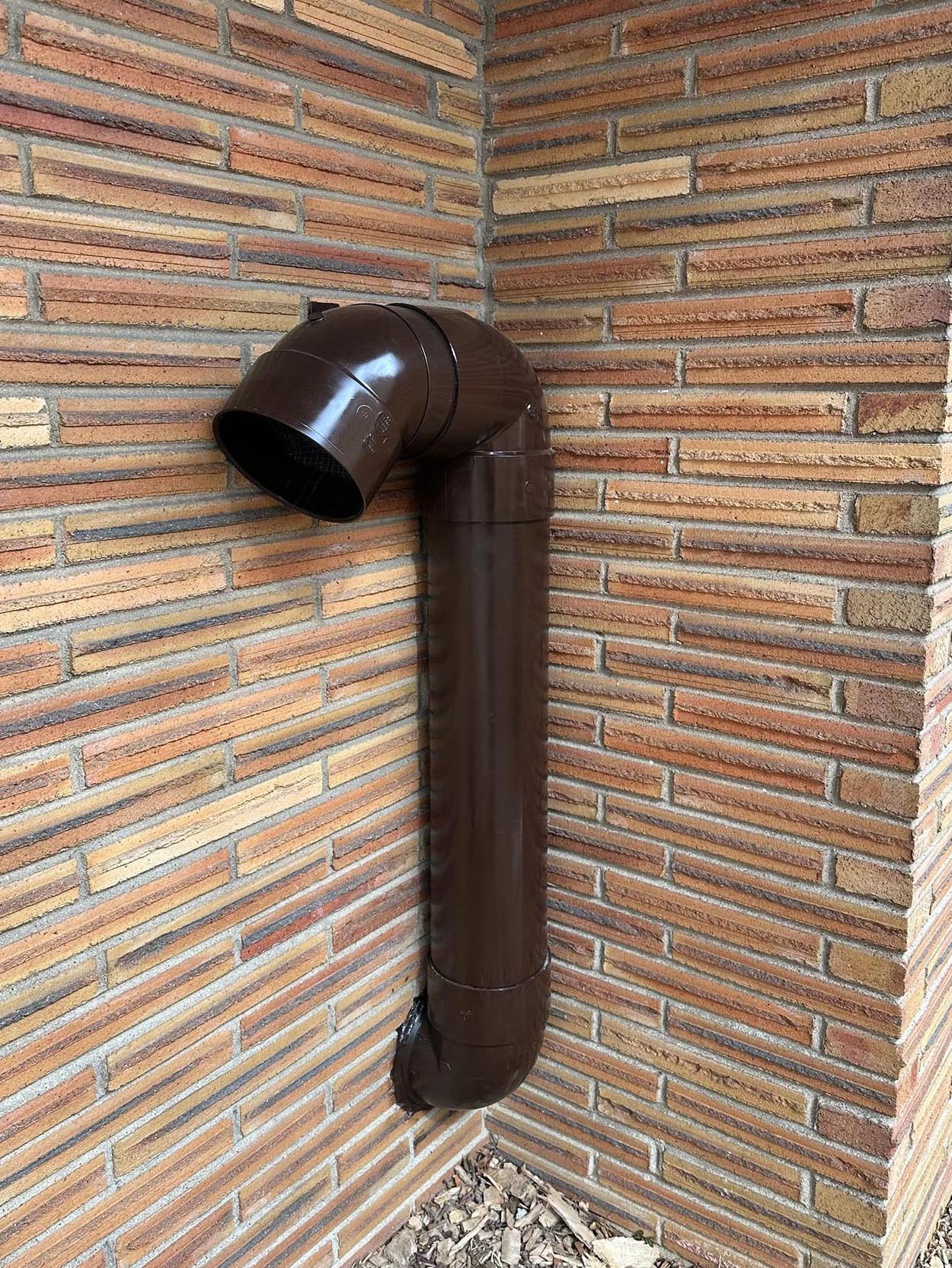 Twin bronze exterior ventilation intake and exhaust hoods on brick façade