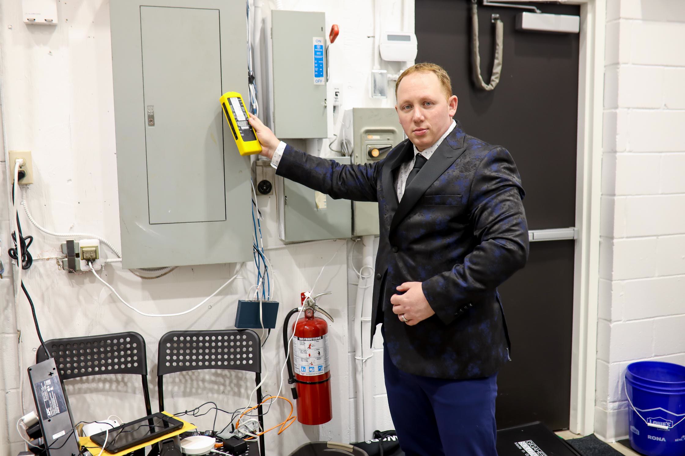Mike Camilleri measuring an electrical panel with a yellow TriField TF2 meter