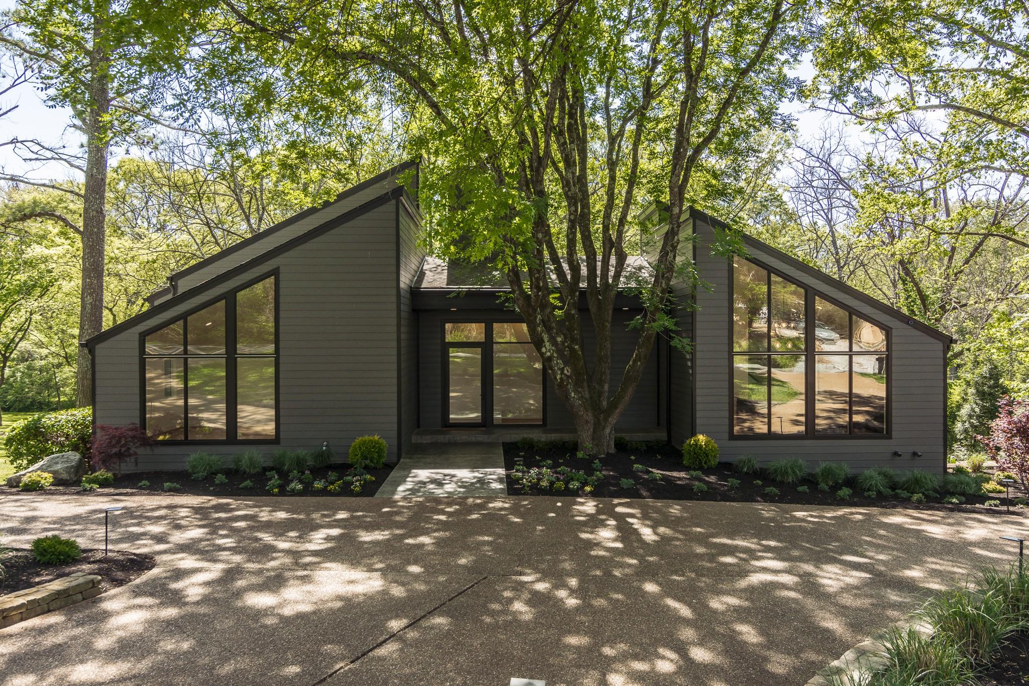 113 Westhampton Pl in Belle Meade, Nashville — architecturally significant modern treehouse home with steeply pitched black gables and floor-to-ceiling windows under a mature tree canopy