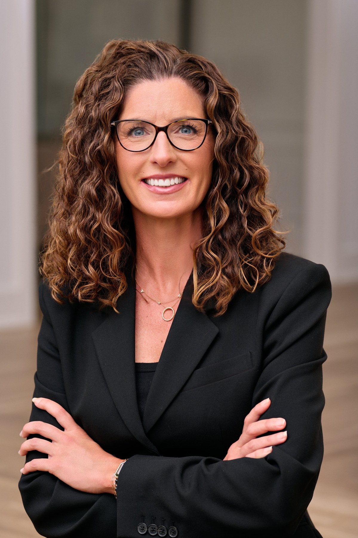 Ashley Boykin — professional editorial portrait, black blazer, warm smile, glasses, curly hair