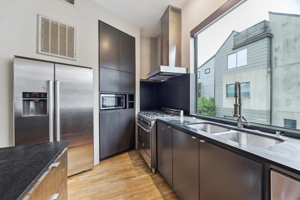 Kitchen at 730 Tulane St D — modern gas range with proper vent hood, natural light through a wide picture window, stainless Bosch appliances